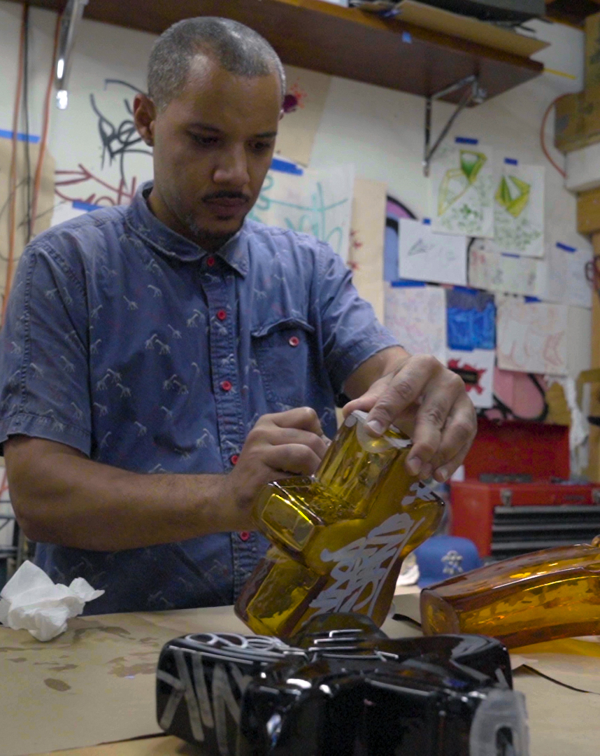 Artist Leo Tecosky uses a white marker on an amber star made of glass