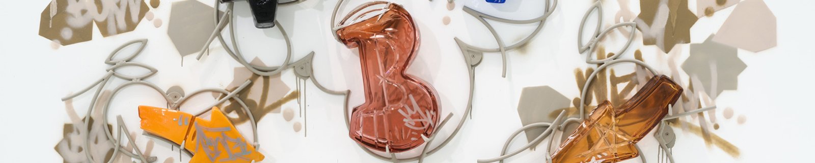 A blown glass letter B in pink, surrounded by orange blown glass arrows